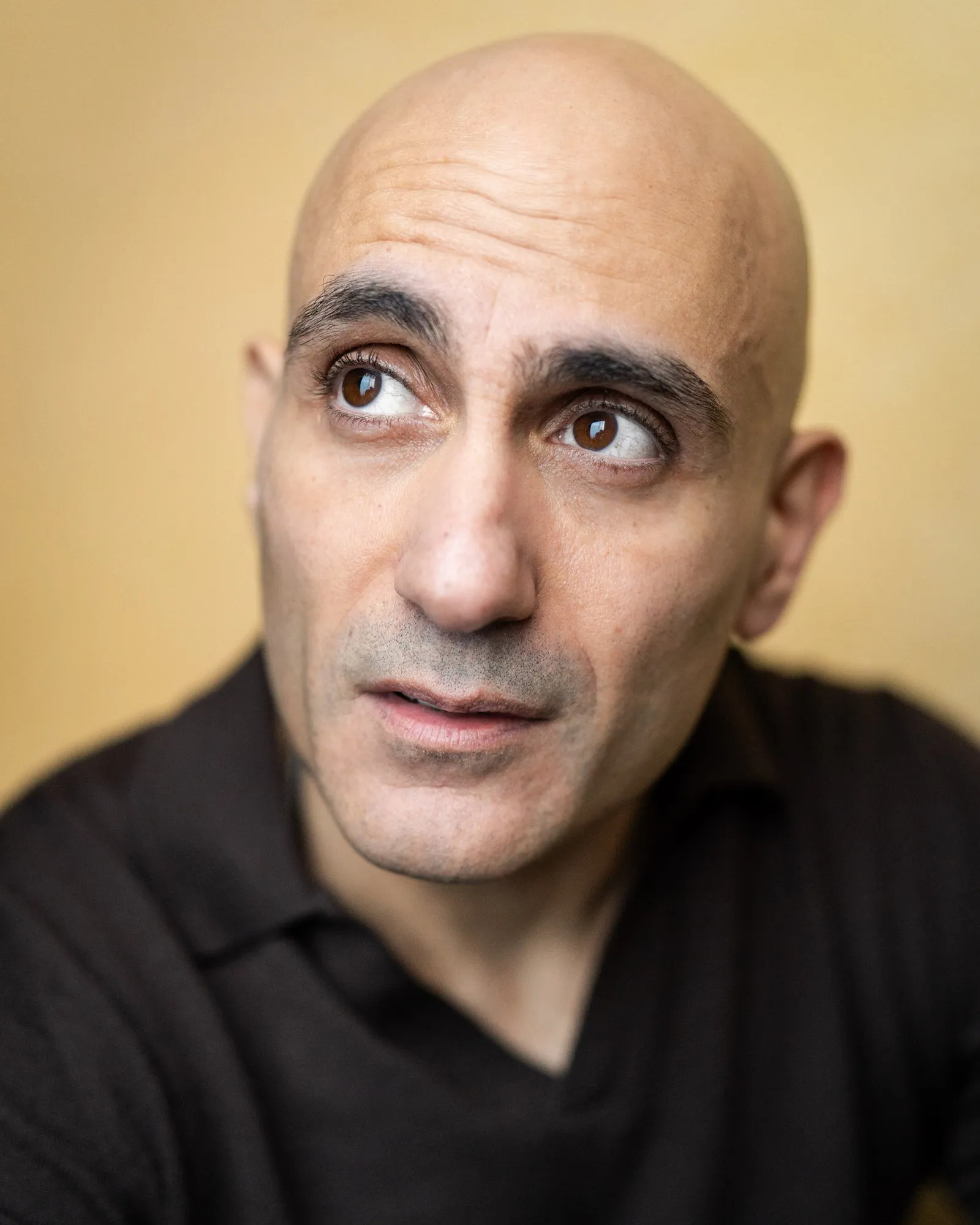 Chris Nicou headshot, looking up, warm background